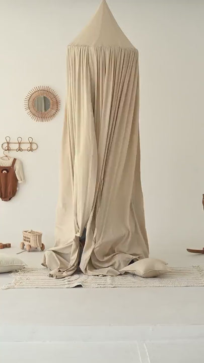 Floor-length beige linen canopy hanging from the ceiling in a neutral kids' room